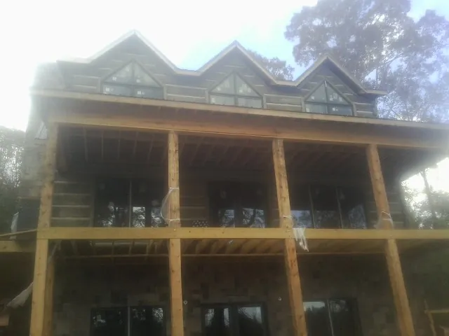 Dormers and porch framing on a large log home under construction — Roof Coating work by our crew in Howell