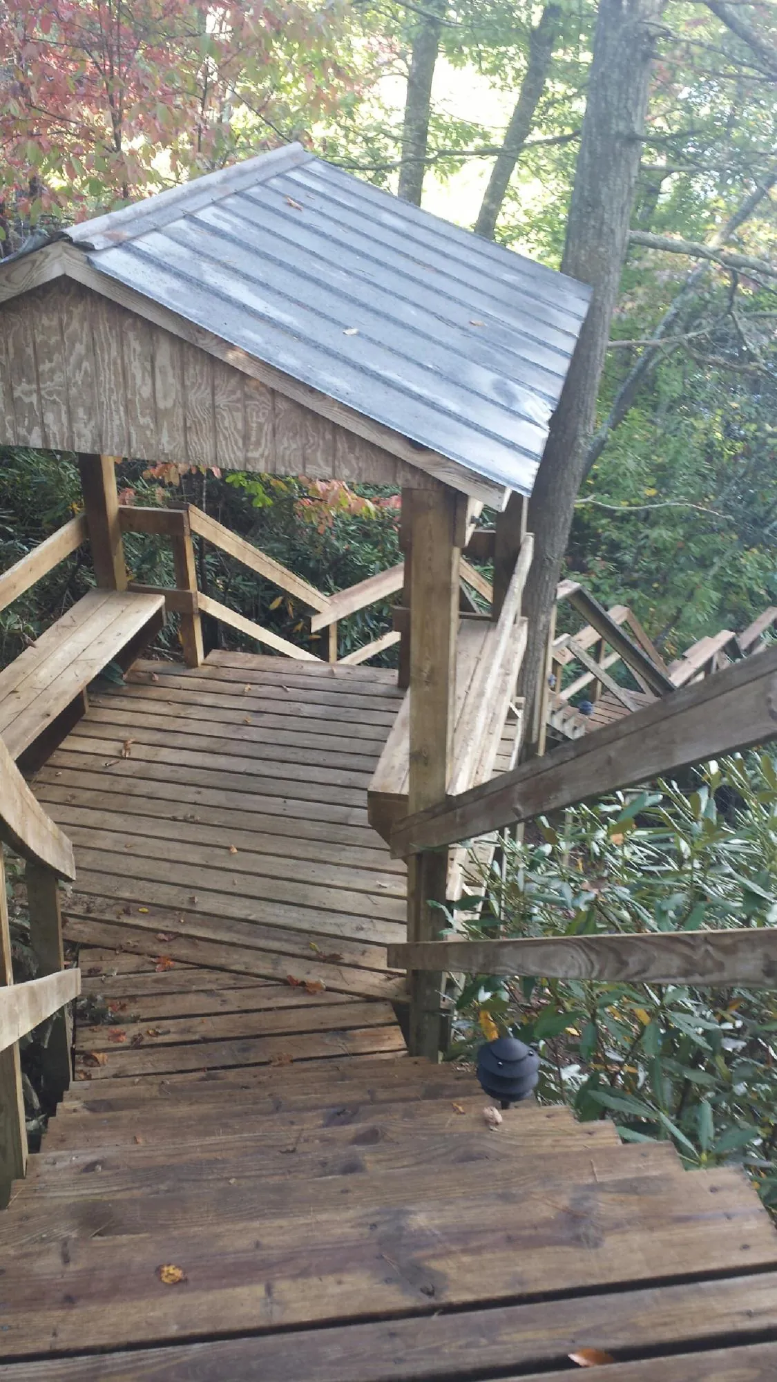 Metal roofed shelter over wooden steps on a wooded walkway — Skylight Repair & Installation work by our crew in Howell